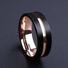 a black and rose gold wedding ring on a dark surface