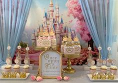 a table topped with cupcakes and cakes in front of a castle wall mural