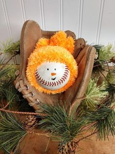 a baseball mitt with a stuffed animal in it on top of some pine needles