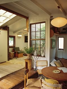 a living room filled with furniture next to a wooden table and chair under a window