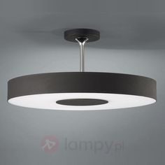 a black and white circular light fixture hanging from the ceiling in a room with grey walls