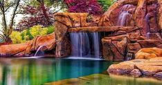 an image of a waterfall in the middle of a pond with rocks and trees around it