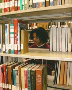 a woman sitting in front of a book shelf filled with books