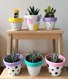 four potted plants sitting on top of a wooden shelf next to each other in different colors