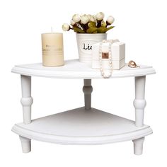 a white table with flowers and a candle on it, sitting next to a vase