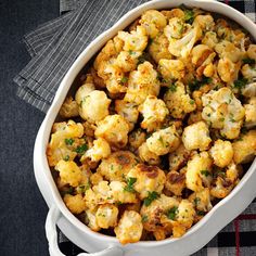 a white dish filled with cauliflower on top of a table