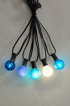 a string of blue and white light bulbs on a white surface with black cords attached to them