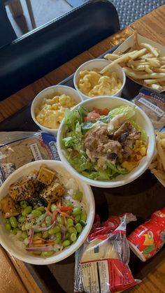 several bowls filled with different types of food on top of a wooden table next to chips