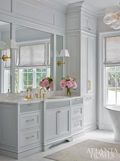 a large bathroom with two sinks, mirrors and bathtub in the middle of it