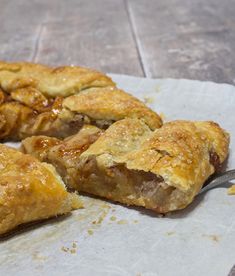 some food is laying on a piece of parchment paper with a knife in it and there are two pieces cut out