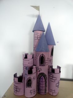 a pink castle made out of cardboard sitting on top of a wooden table next to a white wall