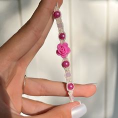 a woman's hand holding a beaded bracelet with pink flowers