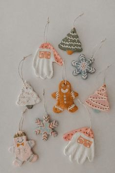 christmas ornaments are hanging from strings on a white surface