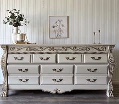 an ornate white dresser with flowers on top