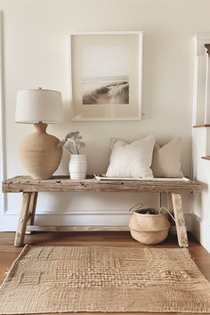 a wooden bench with two vases on top of it next to a rug and lamp