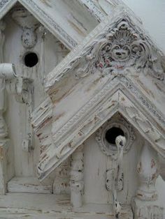 an old white birdhouse with ornate carvings on it's roof and door handles