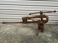 an old rusty metal machine sitting on the ground next to a building with white siding