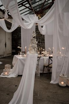 the table is set with white linens and candles