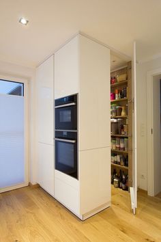 an empty kitchen with white cabinets and wood floors