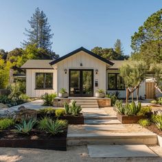 a house that is surrounded by trees and plants in front of the entrance to it