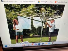 a man and woman standing in front of a computer screen with clothes hanging on it