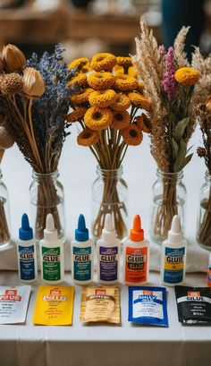 flowers in glass vases sitting on top of a table next to cards and glue