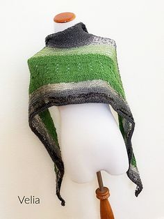 a white mannequin head wearing a green and black striped knitted shawl