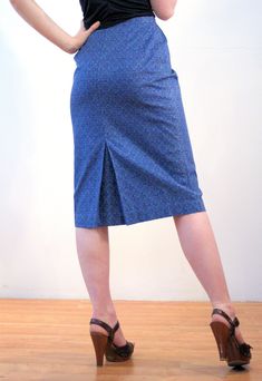 "This is a classic vintage 1960s blue paisley print pencil skirt. It features vertical pleats below the waistband, a center walking vent in the back, and a hem that ends just below the knee. It has a stylized, subtle floral paisley pattern, in turquoise green and navy blue on a deep blue background. The fabric is a sturdy cotton with a satin lining inside at the waist. The skirt closes with a button at the left hip and a 6 inch metal side zipper that is expertly placed, so that it is completely Retro High-waist Blue Skirt, Retro High Waist Blue Skirt, Retro Fitted Knee-length Skirt, Spring Retro Fitted Pencil Skirt, Retro Fitted Pencil Skirt For Spring, Retro Fitted Knee-length Pencil Skirt, Vintage Blue Pleated Bottoms, Blue Fitted Cotton Pencil Skirt, Retro Fitted Midi Skirt