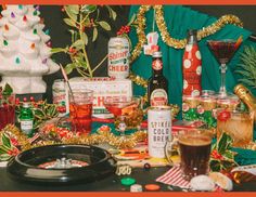 a table topped with lots of alcohol bottles and christmas decorations next to a cake on top of a table