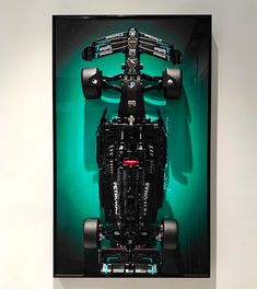 a framed photograph of a race car in green and black colors on a white wall