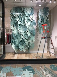 a display case with leaves on it and a ladder in front of the glass door