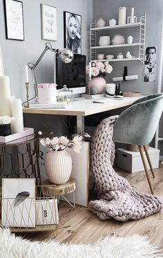 a white desk topped with a computer monitor next to a vase filled with pink flowers