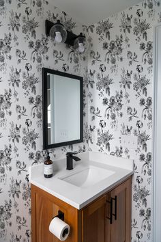 a bathroom vanity with a mirror, sink and toilet paper