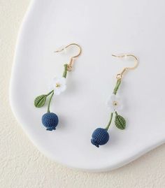 small crocheted cherries and flowers hang from gold earwires on a white plate