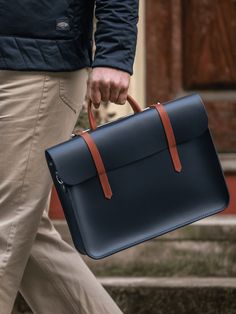 The Music Case is a symphony of stylish design, an exemplary work bag that truly looks like nothing else. It has a distinctive bar closure which slips over its single top handle to effortlessly secure the front flap, keeping your prized possessions masterpiece safely within. Featured here in Navy with Bridle Tan Straps and branded nickel hardware, this two-tone bag stands out as a wonderful unisex colour combination. The bag is made from 100% leather by a team of expert Makers and comes with its Mens Work Bags, Music Bag, Laptop Bag Men, Tan Shoulder Bag, Cloud Bag, Music Case, Bag Stand, Leather Laptop Bag, Leather Skin