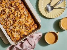 a casserole dish on a table with two cups of coffee