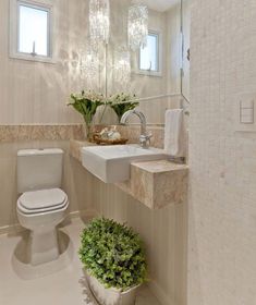 a white toilet sitting next to a sink in a bathroom under a large crystal chandelier