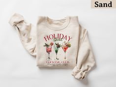 a white sweater with two cocktails on it and the words holiday spirit written in red