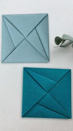 an origami envelope and scissors are on the table next to some folded paper