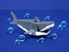 a toy shark with its mouth open on a blue surface surrounded by plastic curlers