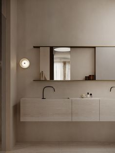 a bathroom with two sinks, mirrors and lights on the wall next to each other