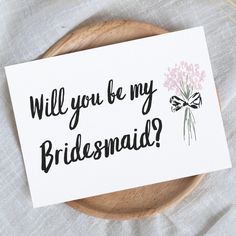 a card with the words will you be my bridesmaid? and a bouquet of flowers