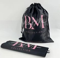 a black bag with pink letters on the front and bottom, next to a pair of scissors