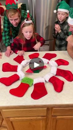 a group of people standing around a table with christmas decorations on it and one person making an ornament