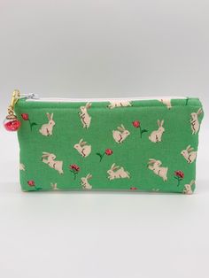 "One can never have enough pouches!  This \"Bunnies and Roses \" theme zipper pouch would make a useful and adorable gift for that someone special.   This zipper pouch would be ideal  for holding cosmetics, toiletries, money, ID and credit cards, jewelry, ear buds, small electronic devices, cords, school supplies, and other small trinkets.     This pouch is made with a spring theme cotton fabric in a whimsical \"Bunnies and Roses\" print, pink lining, interfacing, zipper, confetti ball charm or Green Pouch Pencil Case With Zipper, Green Pencil Case With Zipper Closure, Cute Zipper Pouch Pencil Case Gift, Cute Green Zipper Pouch Pencil Case, Green Pencil Case With Zipper Closure For Gift, Green Pencil Case With Zipper Closure As Gift, Green Zippered Pencil Case, Green Zipper Cosmetic Bag For Personal Use, Green Cosmetic Bag With Zipper Closure For Personal Use