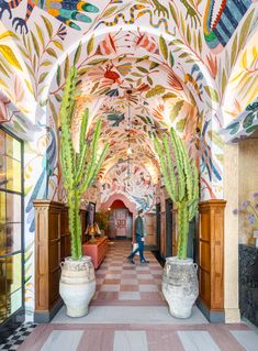 the hallway is decorated with colorfully painted murals and large cactus plants in white vases