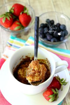 a spoon with some food in it on a plate next to strawberries and blueberries