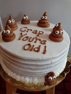 a white cake with chocolate frosting and eyes on top that says crap you're old