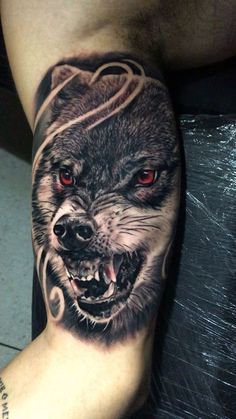 a man's leg with a wolf tattoo on it, and red eyes in the center