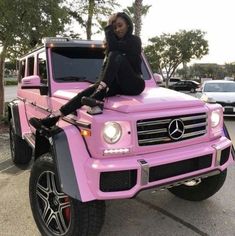 a woman sitting on top of a pink mercedes benz